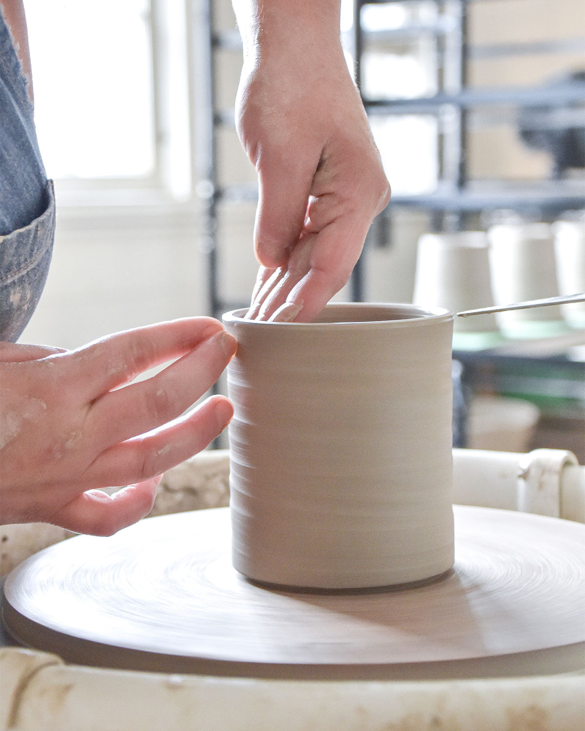 shaping a clay cylinder on a wheel.