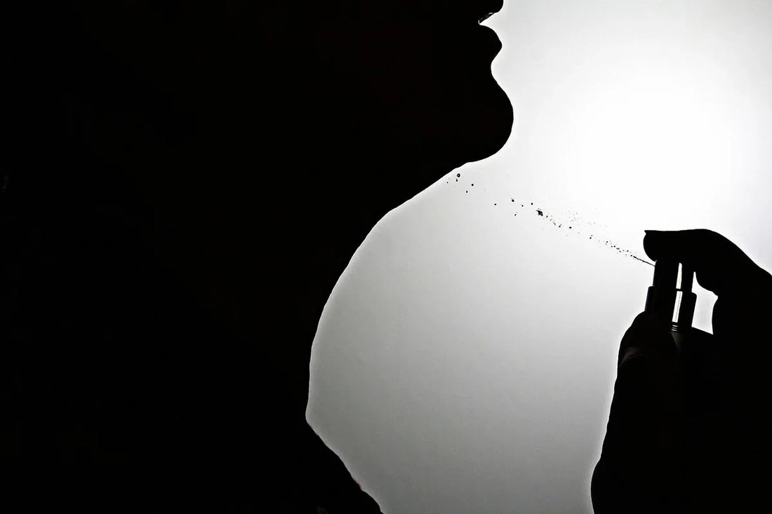 Silhouette of a person spraying perfume on their neck showing how to apply perfume