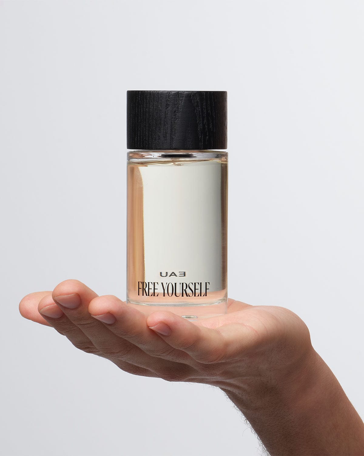 UAU Free Yourself Eau de Parfum 100ml bottle held in hand.